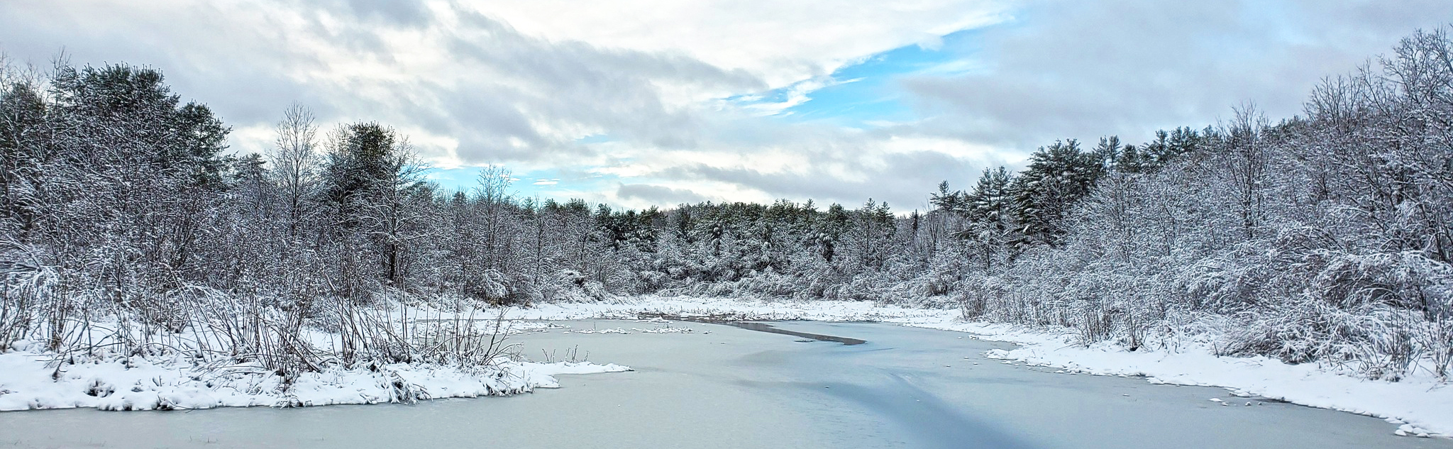 Crescent Lake in the Unity NH covered in ice with snow-covered trees pine all around it.
